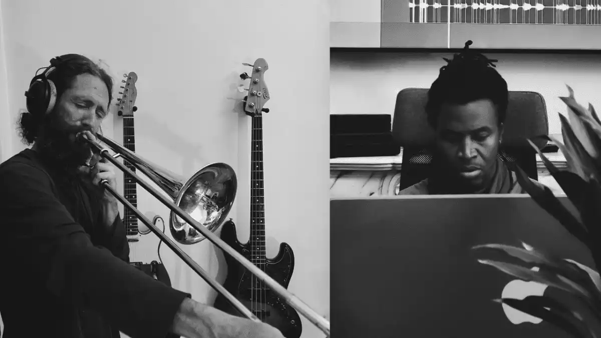 Deux musiciens en séance de travail : l'un joue du trombone au casque, l'autre compose sur son MacBook